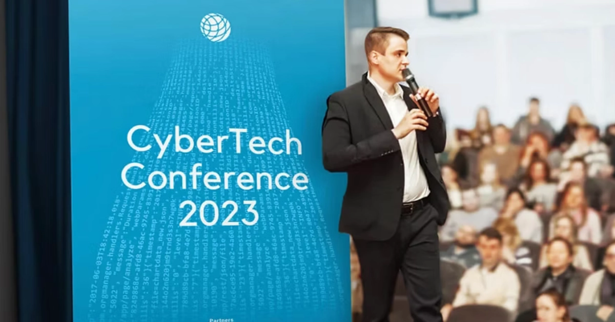 CyberTech conference presentation screen with speaker addressing audience at business event
